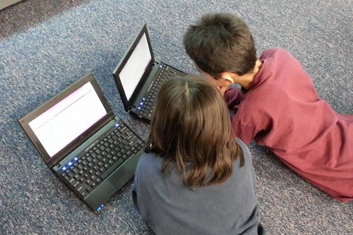 Two children using laptops